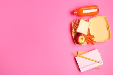 Photo of Lunch box with snacks, bottle of juice and stationery on pink background, flat lay. Space for text