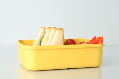 Photo of Lunch box with sandwiches and vegetables on light background