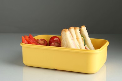 Photo of Lunch box with sandwiches and vegetables on light table