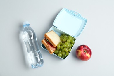 Photo of Lunch box with snacks, apple and bottle of water on white background, flat lay