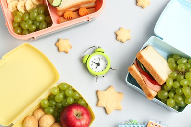 Photo of Lunch box with snacks, alarm clock and stationery on white background, flat lay