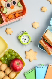 Photo of Lunch box with snacks, alarm clock and stationery on white background, flat lay