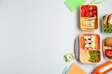 Photo of Lunch boxes with snacks, alarm clock and stationery on white background, flat lay. Space for text