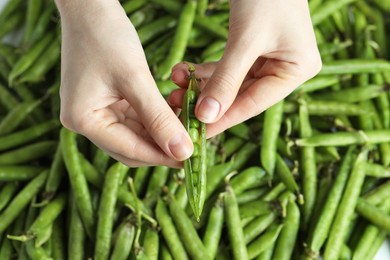 Photo of Woman opening fresh green pea pods, top view