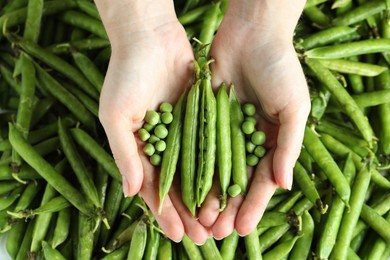 Photo of Woman holding fresh green pea pods, top view