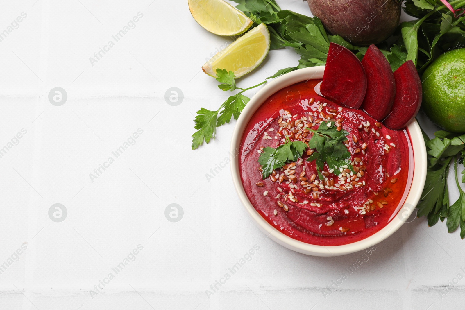 Photo of Tasty beetroot hummus in bowl and products on white table, flat lay. Space for text