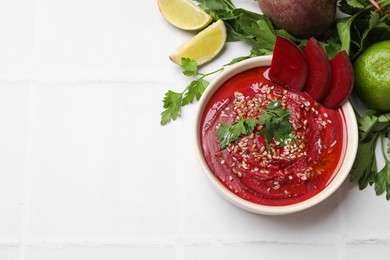 Photo of Tasty beetroot hummus in bowl and products on white table, flat lay. Space for text