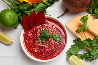 Photo of Tasty beetroot hummus in bowl and products on white table, flat lay