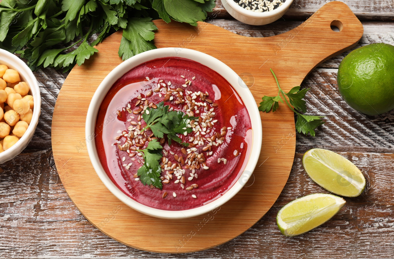 Photo of Tasty beetroot hummus in bowl and products on wooden table, flat lay