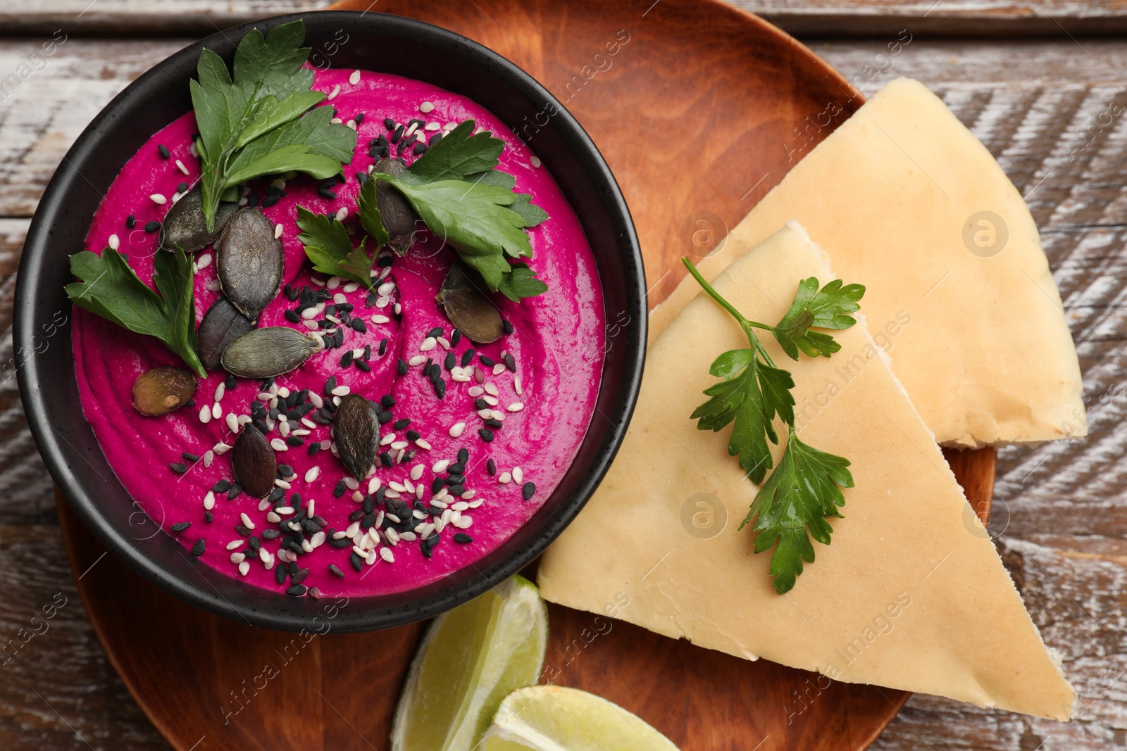 Photo of Tasty beetroot hummus in bowl and products on wooden table, top view