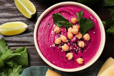 Photo of Tasty beetroot hummus in bowl and products on wooden table, flat lay