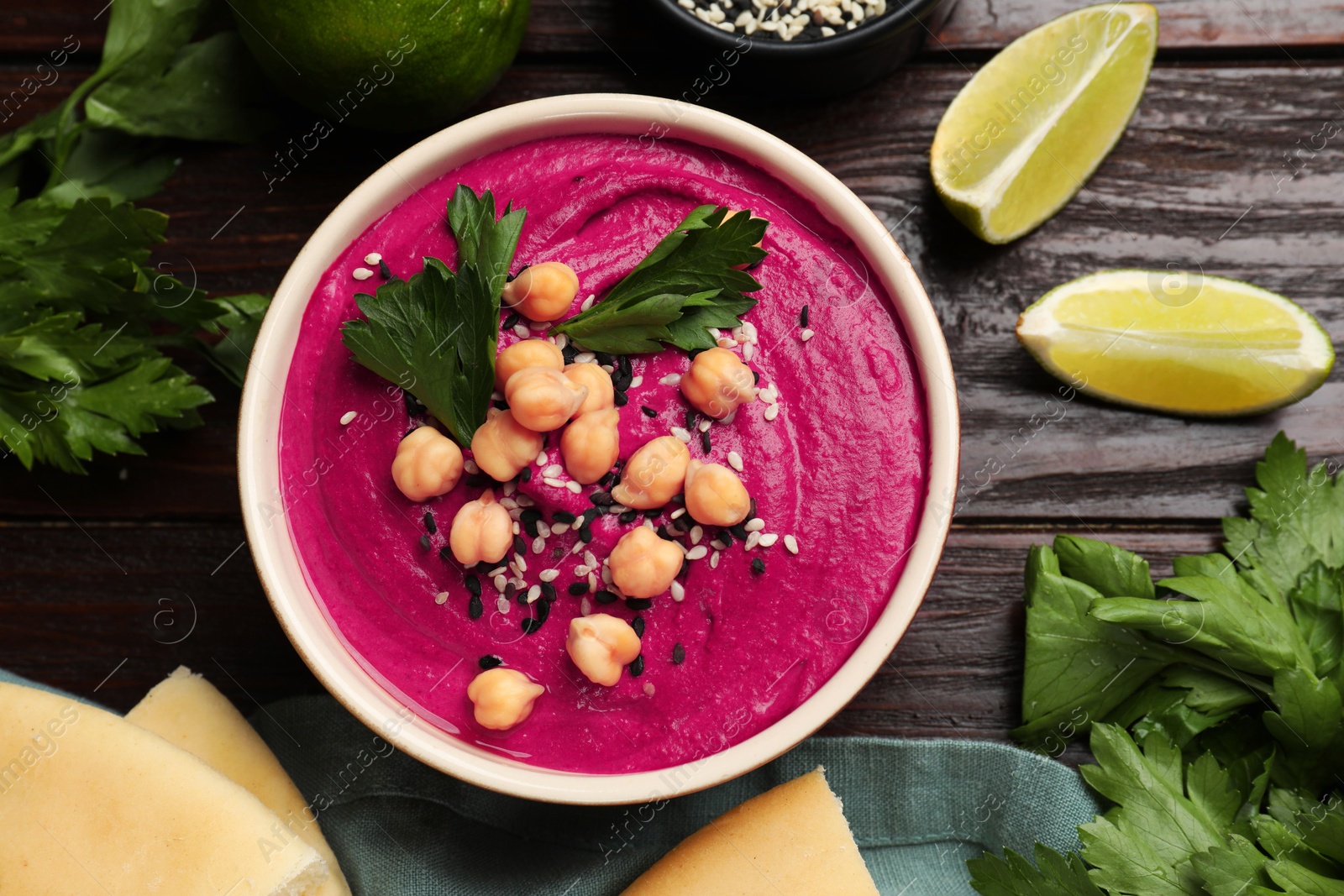 Photo of Tasty beetroot hummus in bowl and products on wooden table, flat lay