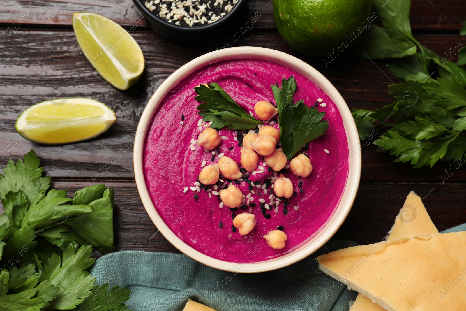 Photo of Tasty beetroot hummus in bowl and products on wooden table, flat lay