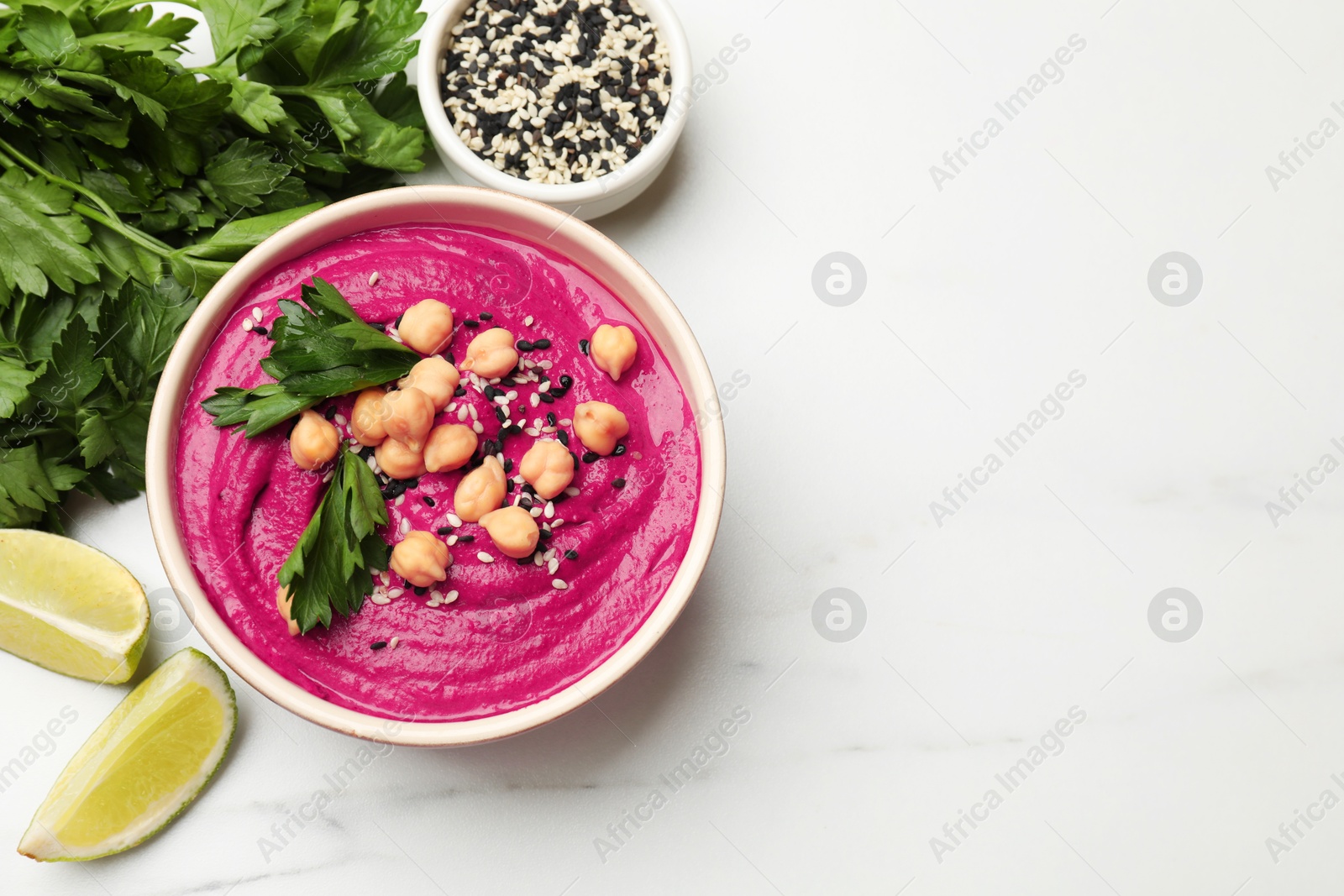 Photo of Tasty beetroot hummus in bowl and products on white marble table, flat lay. Space for text