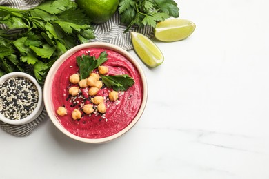 Photo of Tasty beetroot hummus in bowl and products on white marble table, flat lay. Space for text