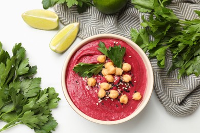 Photo of Tasty beetroot hummus in bowl and products on white marble table, flat lay