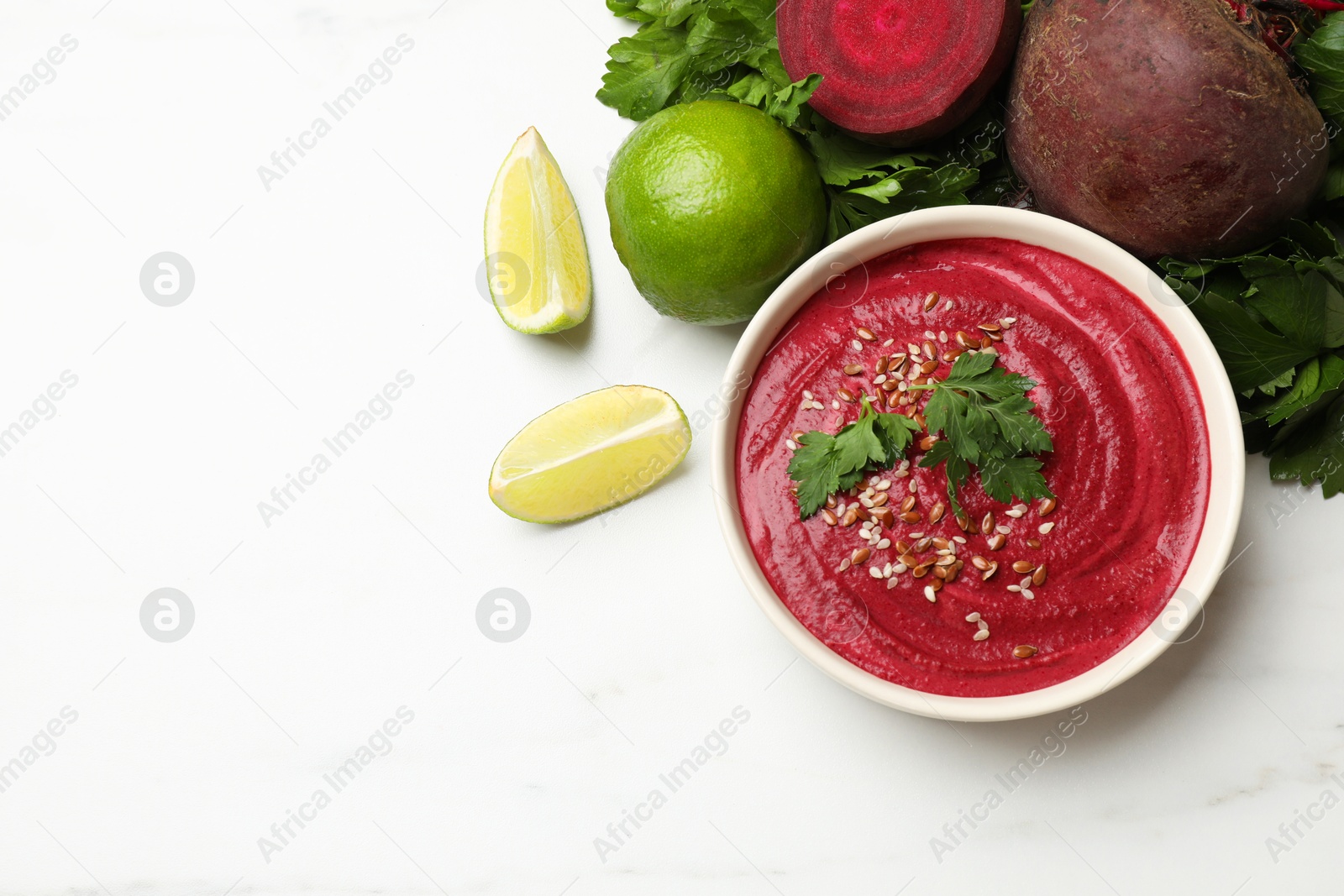 Photo of Tasty beetroot hummus in bowl and products on white marble table, flat lay. Space for text