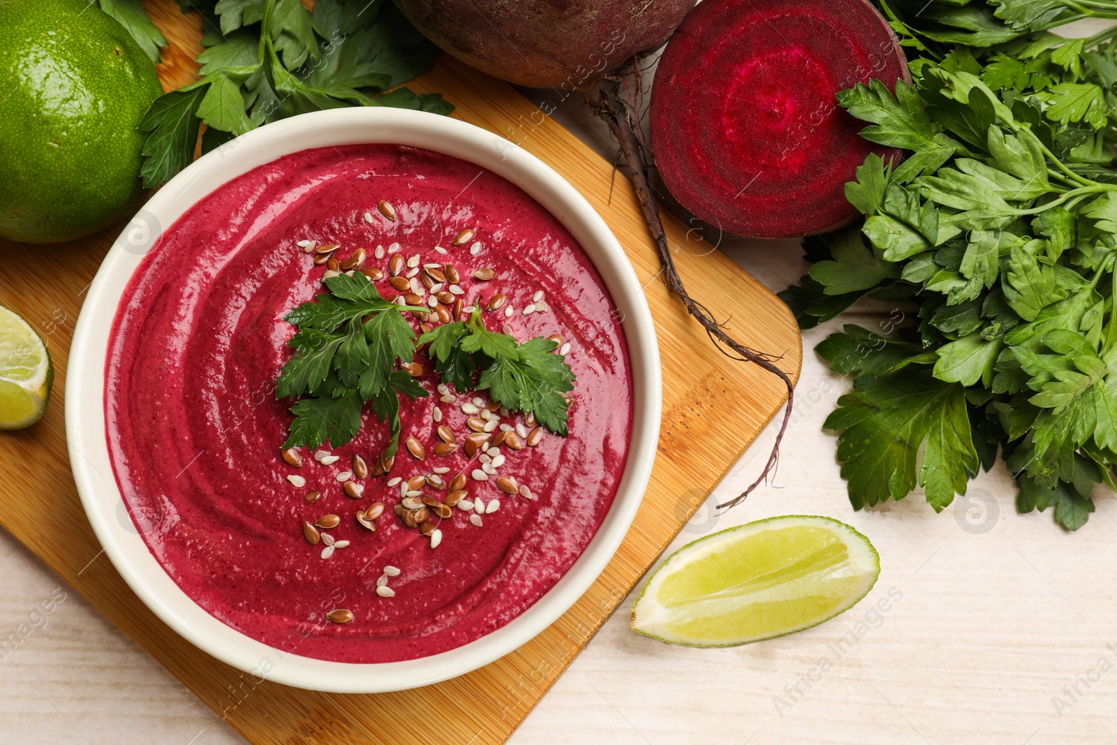 Photo of Tasty beetroot hummus in bowl and products on light wooden table, flat lay