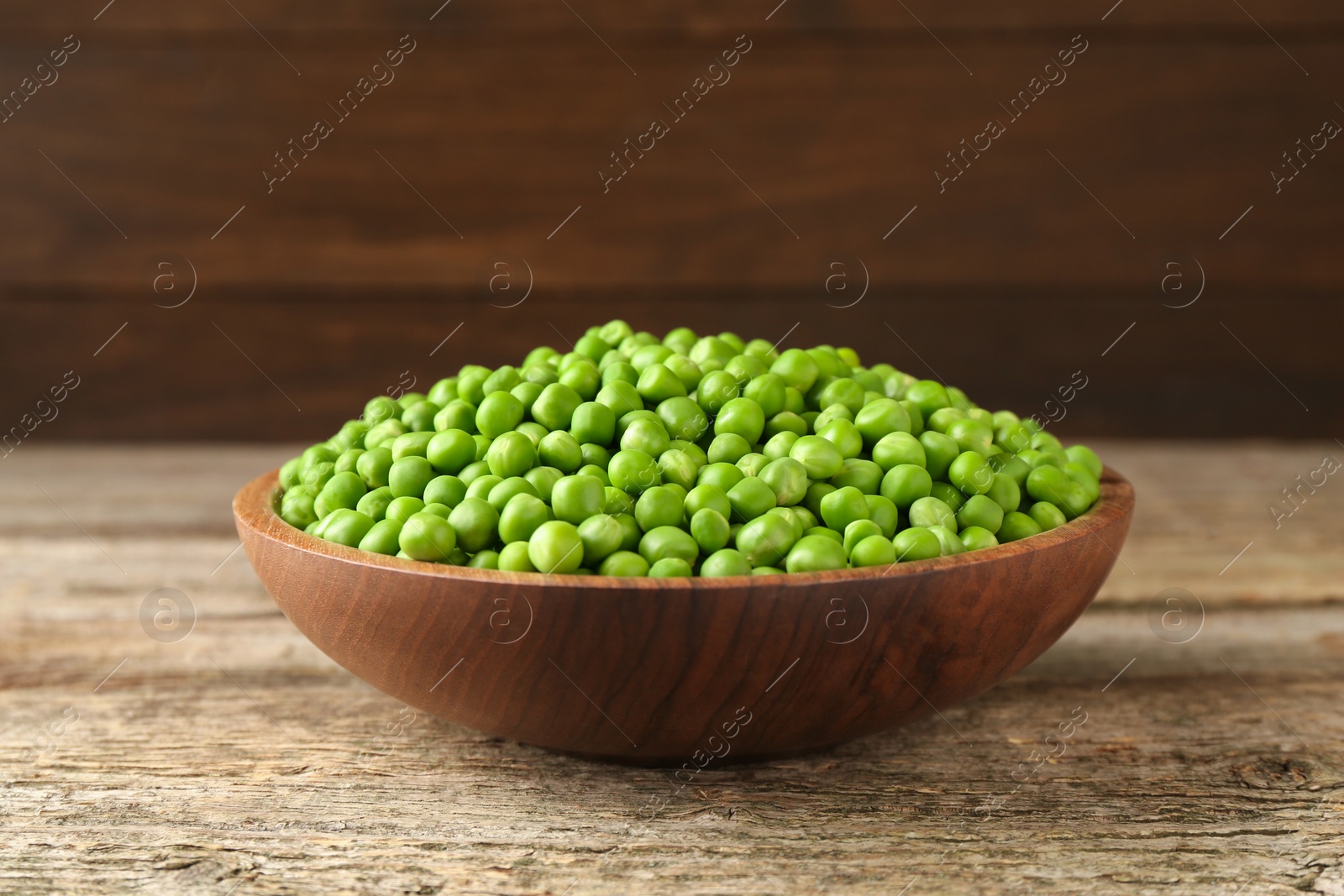 Photo of Fresh green peas in bowl on wooden table