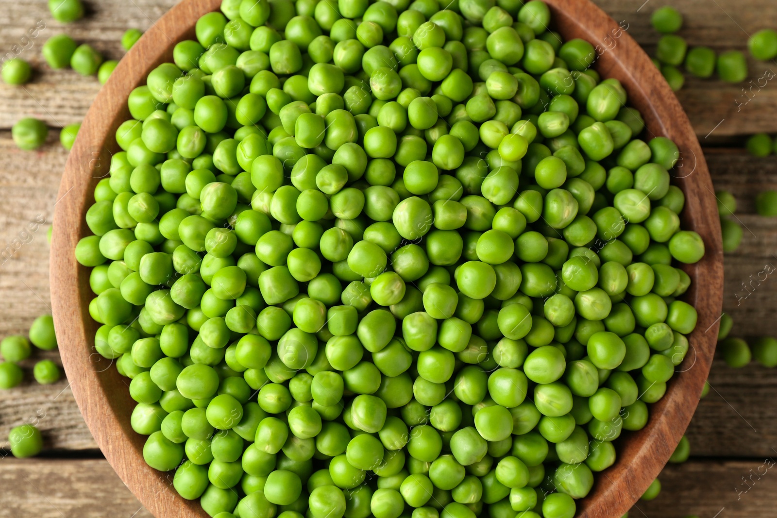 Photo of Fresh green peas in bowl on wooden table, top view