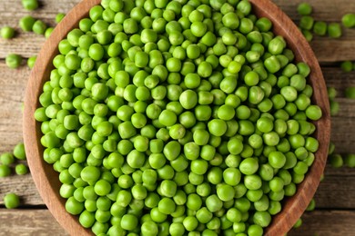 Photo of Fresh green peas in bowl on wooden table, top view