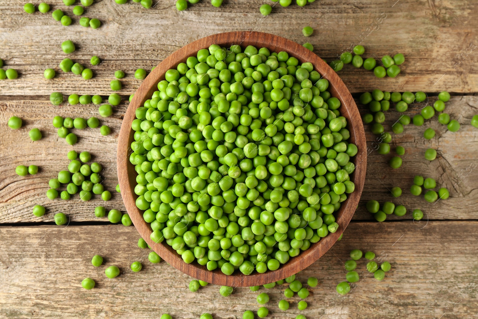 Photo of Fresh green peas in bowl on wooden table, top view