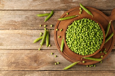 Photo of Fresh green peas in bowl and pods on wooden table, flat lay. Space for text