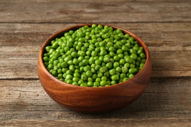 Fresh green peas in bowl on wooden table