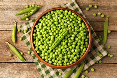 Fresh green peas and pods on wooden table, flat lay