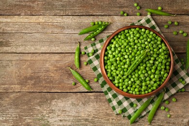 Fresh green peas and pods on wooden table, flat lay. Space for text