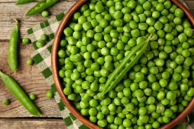 Fresh green peas and pods on wooden table, flat lay