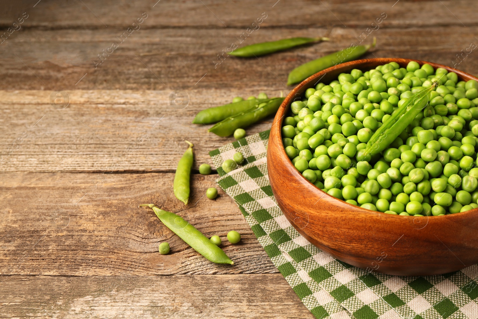 Photo of Fresh green peas and pods on wooden table, space for text