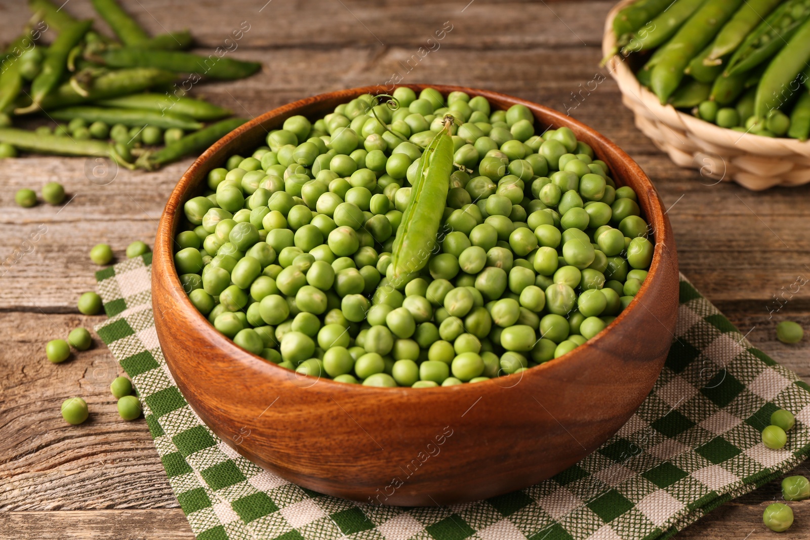 Photo of Fresh green peas and pods in bowl on wooden table, closeup