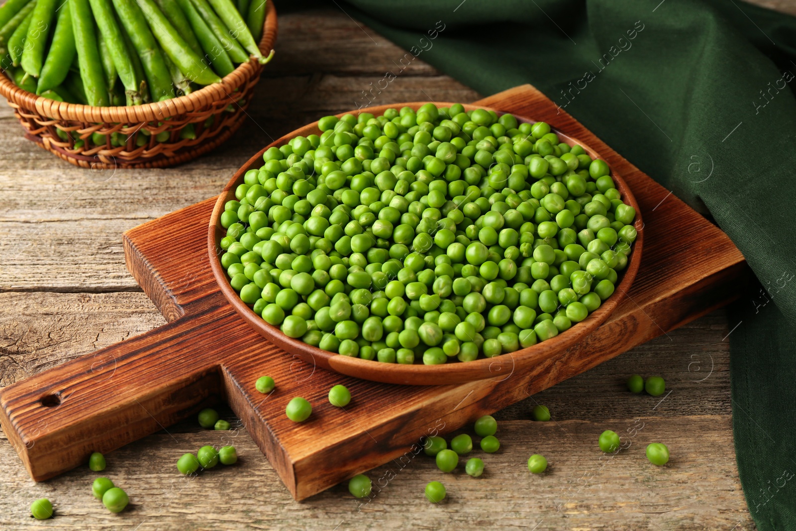 Photo of Fresh green peas in bowl and pods on wooden table