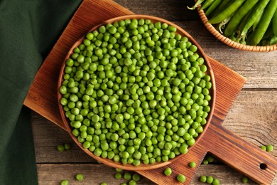 Fresh green peas and pods on wooden table, flat lay