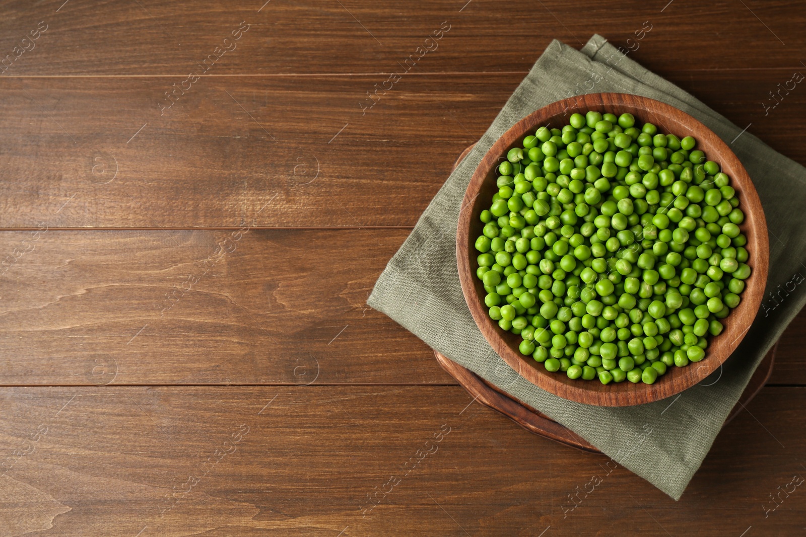 Photo of Fresh green peas in bowl on wooden table, top view. Space for text