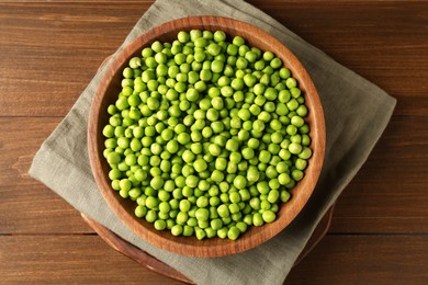 Photo of Fresh green peas in bowl on wooden table, top view