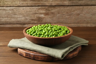 Photo of Fresh green peas in bowl on wooden table