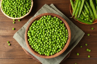 Fresh green peas and pods on wooden table, flat lay