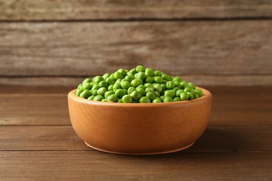 Photo of Fresh green peas in bowl on wooden table