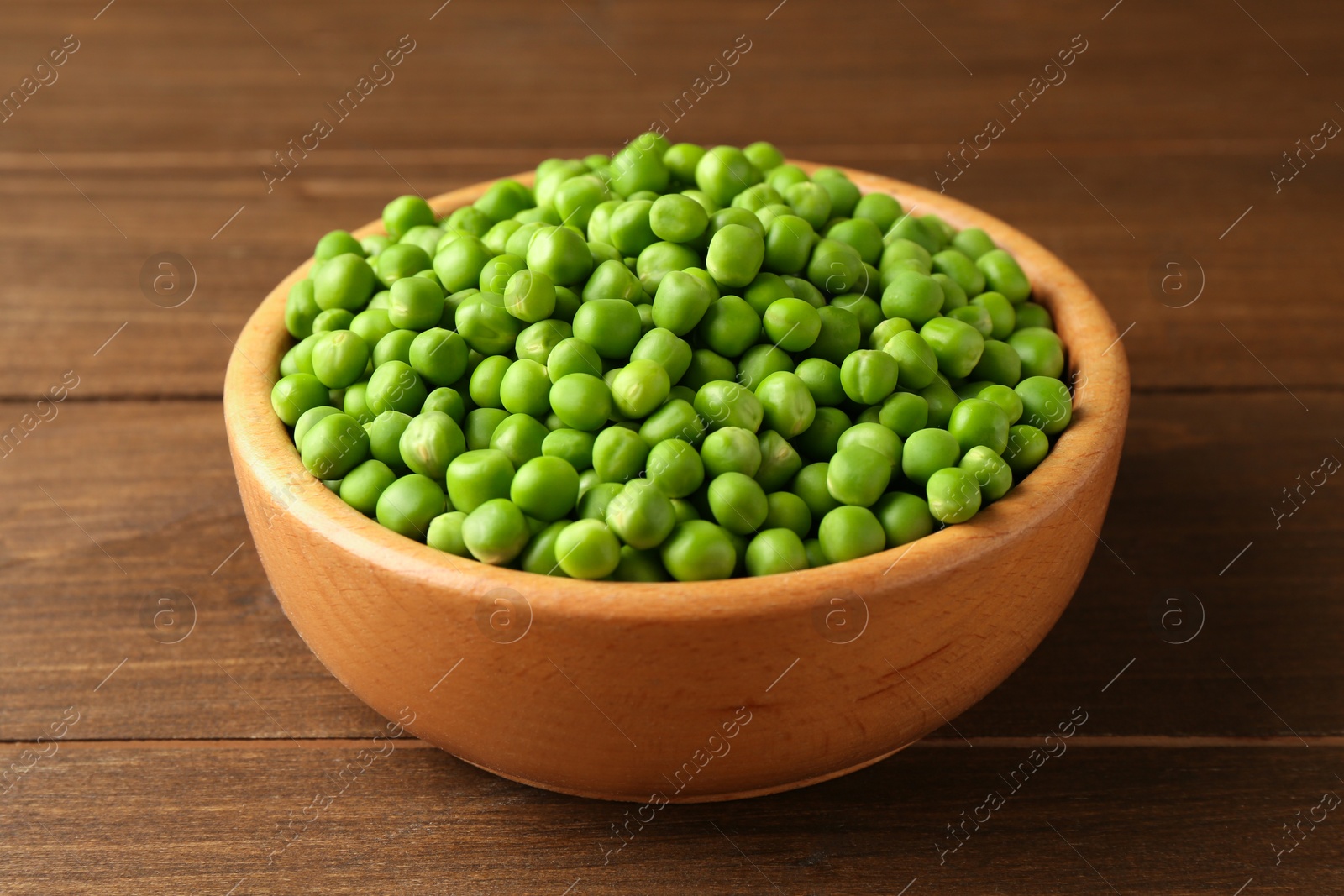 Photo of Fresh green peas in bowl on wooden table, closeup