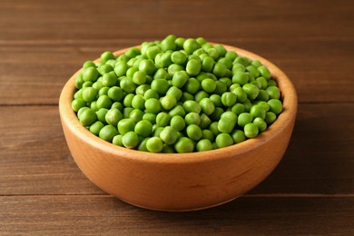 Photo of Fresh green peas in bowl on wooden table, closeup