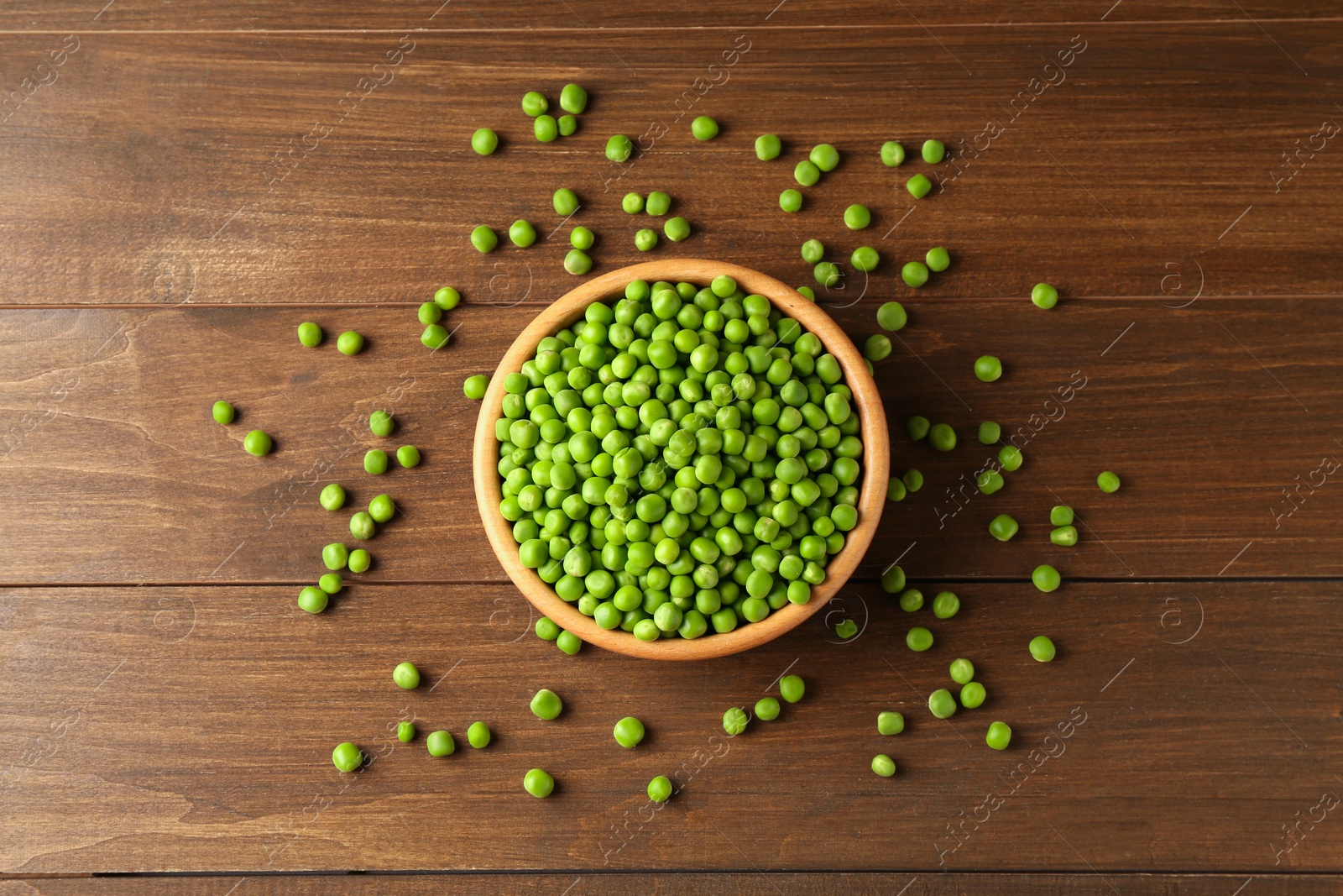 Photo of Fresh green peas in bowl on wooden table, top view