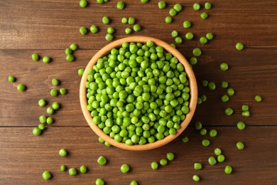 Photo of Fresh green peas in bowl on wooden table, top view