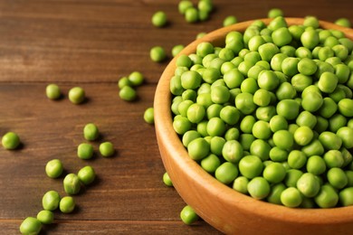 Photo of Fresh green peas in bowl on wooden table, closeup