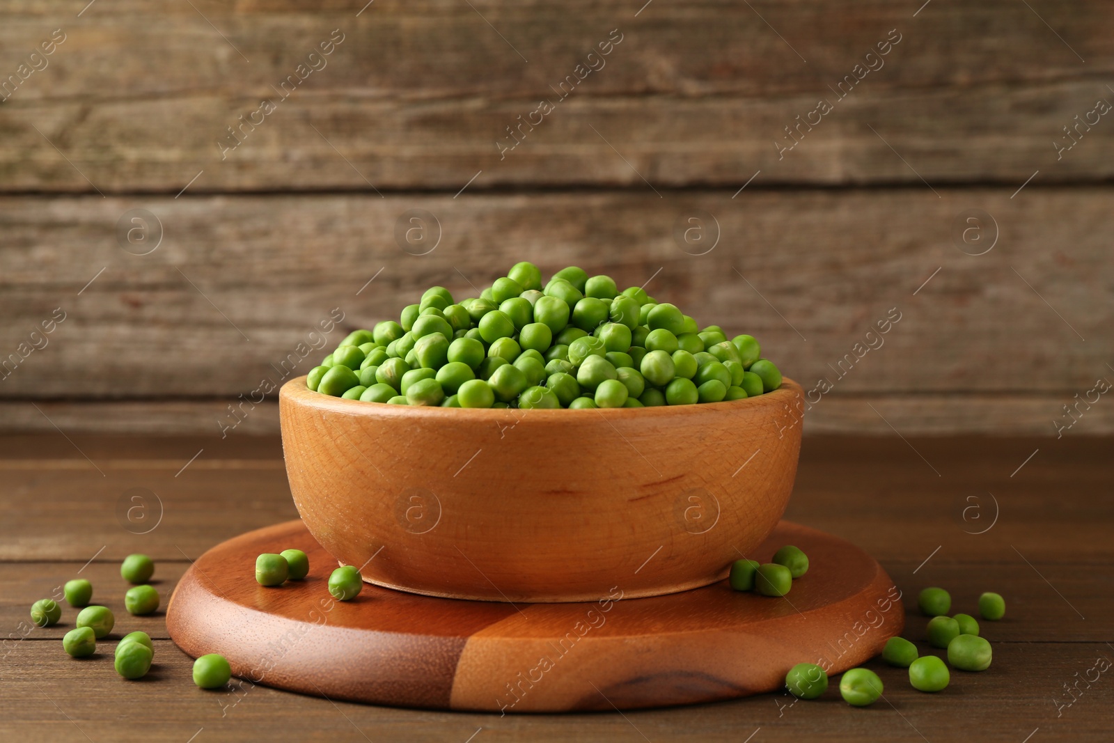 Photo of Fresh green peas in bowl on wooden table