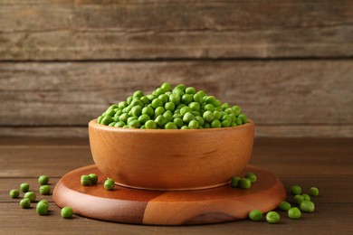 Photo of Fresh green peas in bowl on wooden table