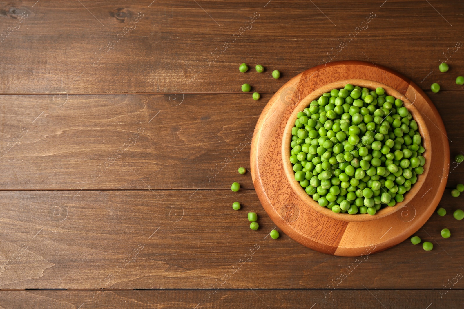 Photo of Fresh green peas in bowl on wooden table, top view. Space for text