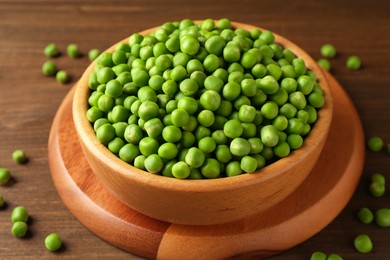 Fresh green peas in bowl on wooden table