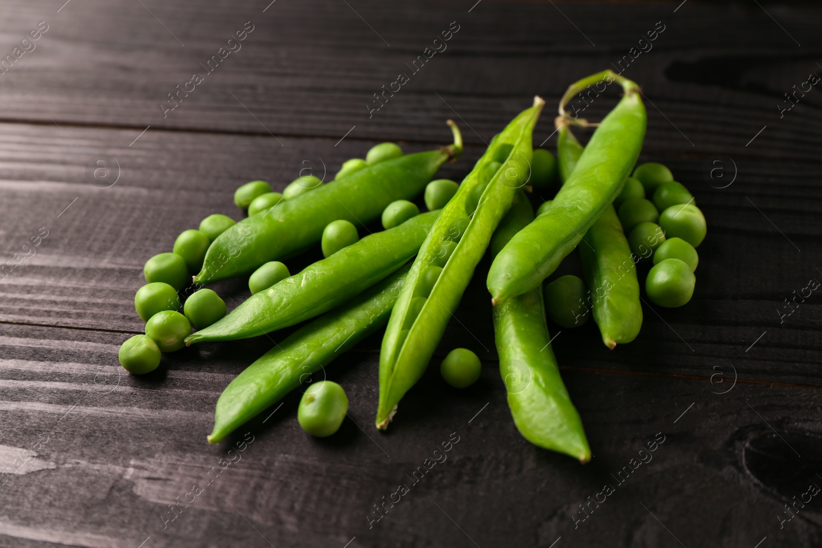 Photo of Fresh green peas and pods on black wooden table